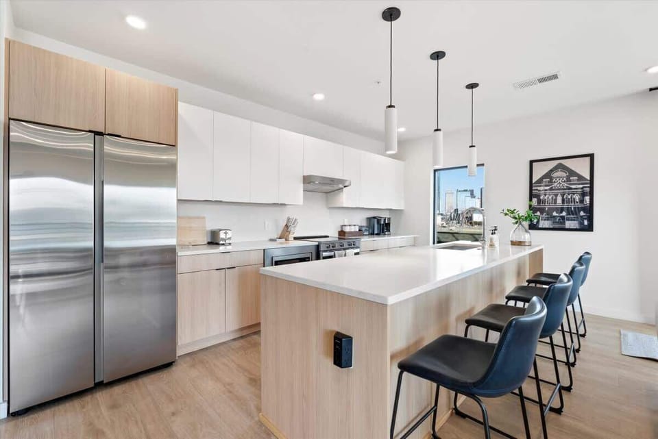 Modern white cabinetry, stainless steel appliances, kitchen island, and a view of the city skyline 