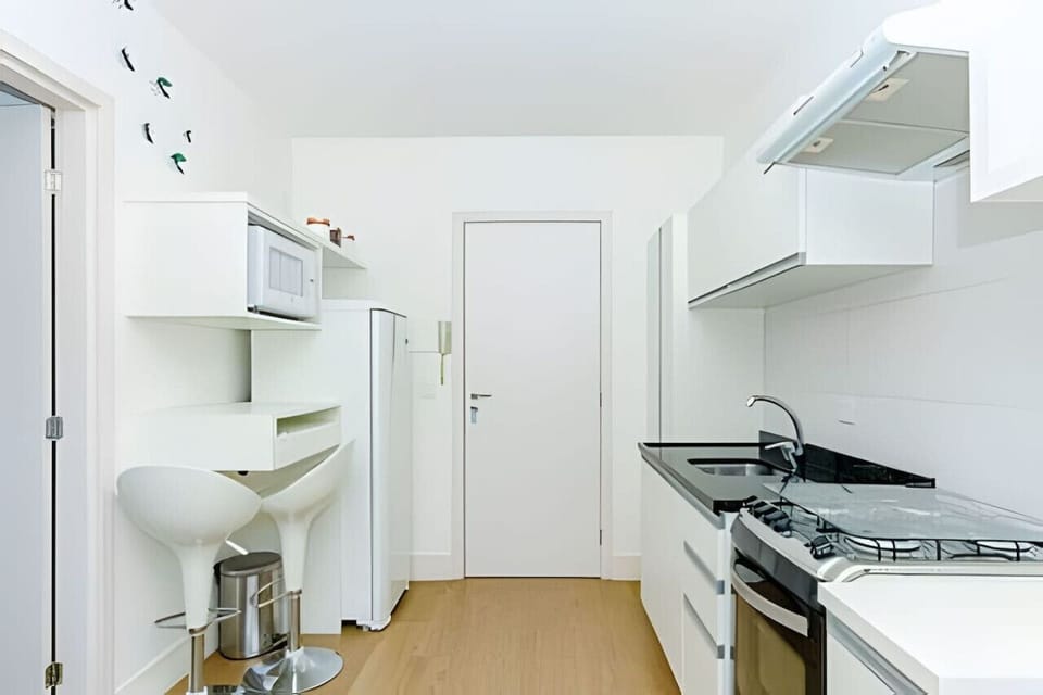 Cozinha moderna equipada com micro-ondas, geladeira, exaustor, fogão, pia, armários e mesa para alimentação de 2 lugares.