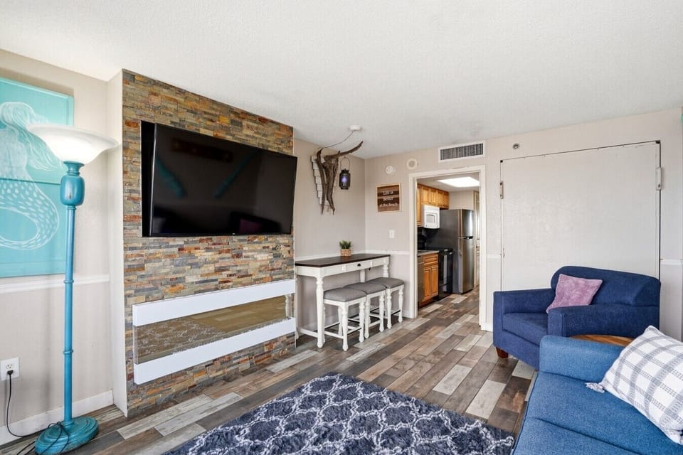 Livingroom features a big screen tv full-sized sofa, upholstered chair, and a Murphy Bed