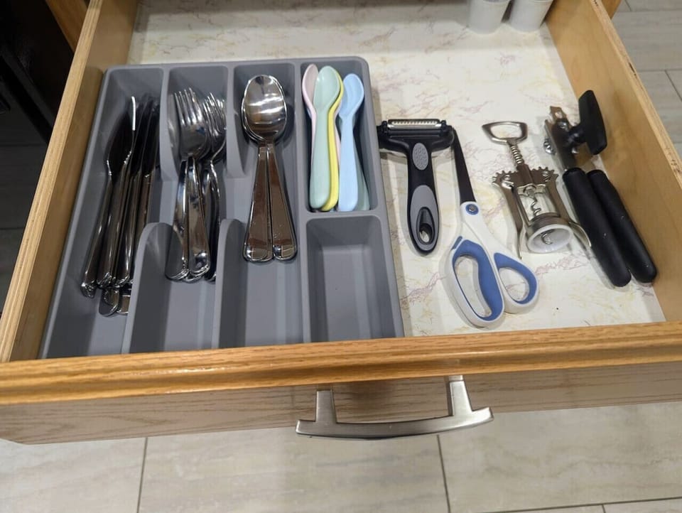 Organized flatware drawer with forks, spoons, knives, scissors, and can opener — everything in one place so cooking and dining is smooth from the first night.