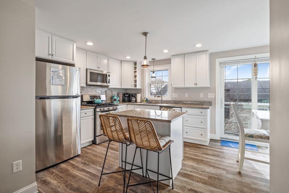 Fully equipped kitchen with updated appliances, coffee provided, and an island with seating for two.