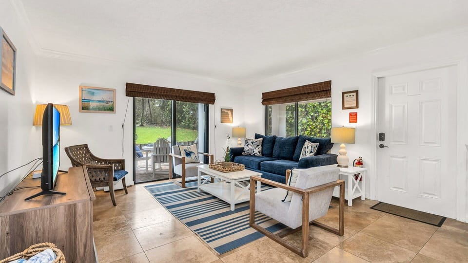 Bright, cozy, and coastal-chic. This inviting living room is the perfect place to unwind after a beach day—featuring comfy seating, tropical touches, and serene views just beyond the sliding doors
