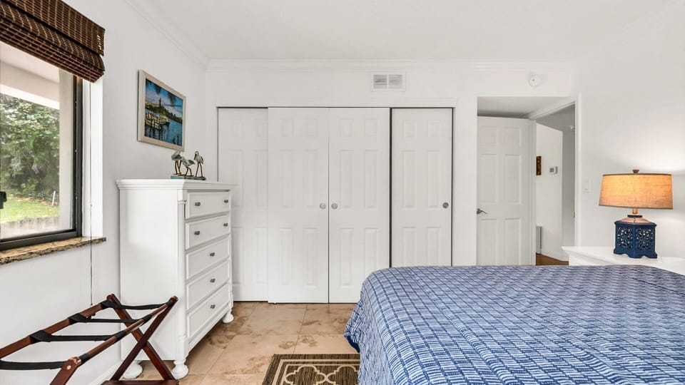 This bright and breezy queen bedroom offers a peaceful retreat with lush views, a spacious dresser, and ample closet space to unpack and settle in. Perfect for a restful night's sleep after a day in the sun.