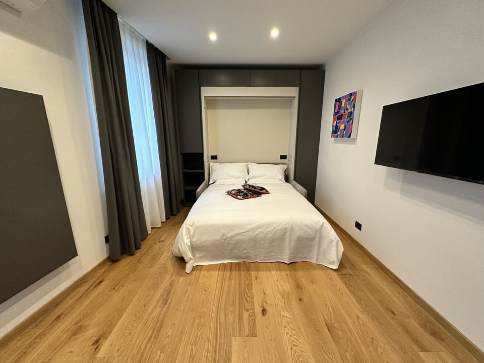Bedroom/Living room equipped with a closet with a drop-down bed, SKY TV, closet for clothing, folding table and four folding chairs
