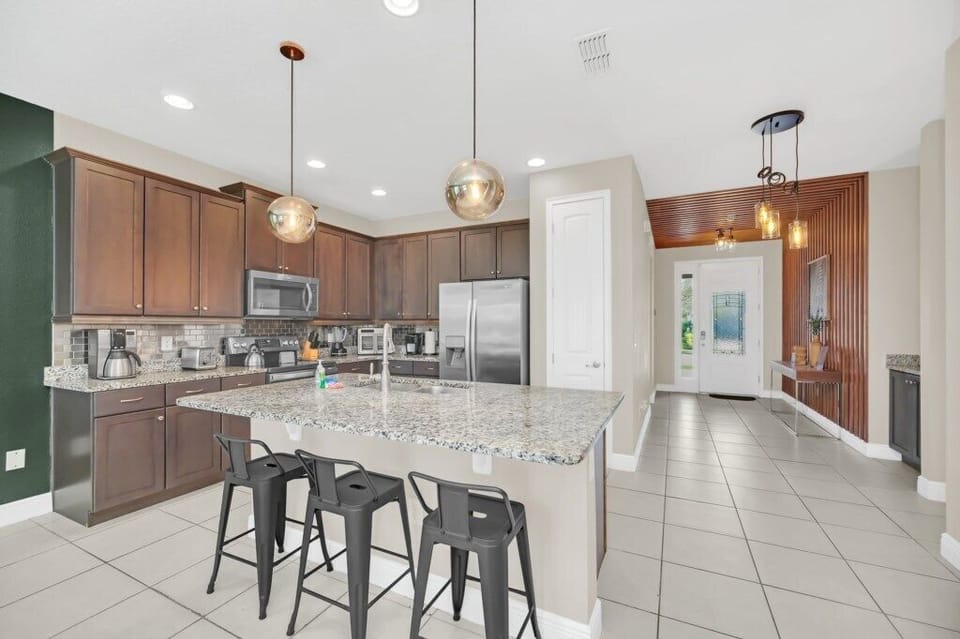 Modern kitchen with spacious granite countertops, stainless steel appliances, and a breakfast bar with seating.