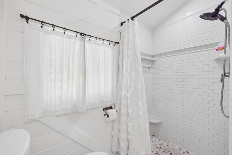 Clean, chic bathroom including shower, toilet, and single vanity.