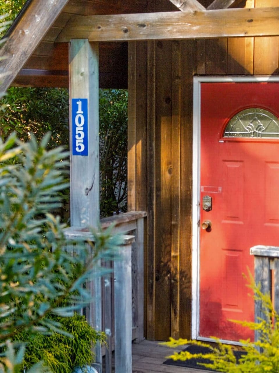Welcoming cabin entrance tucked into lush greenery—your peaceful West Coast escape begins here