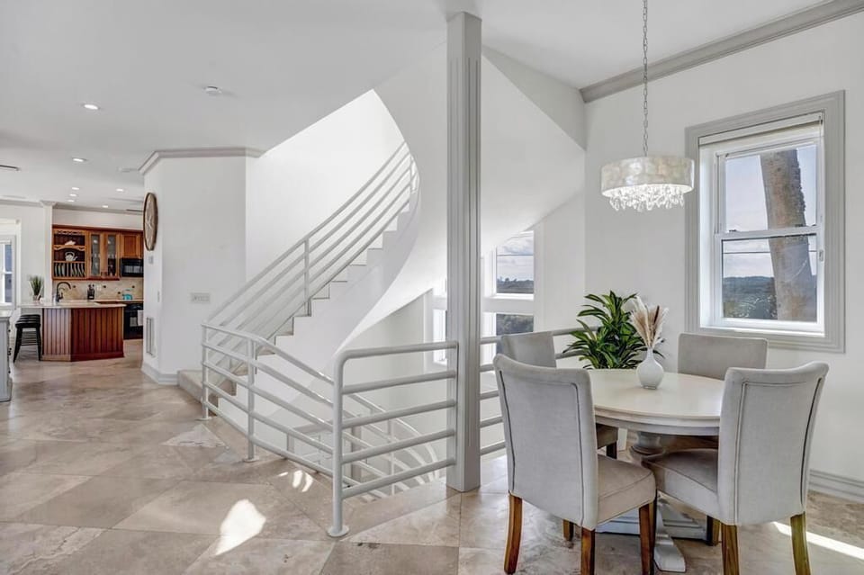 - Bright breakfast nook with coastal views and modern round table for four
- Curved stairwell adds an architectural centerpiece near open concept layout
- Natural light pours in from windows all around this airy corner spot