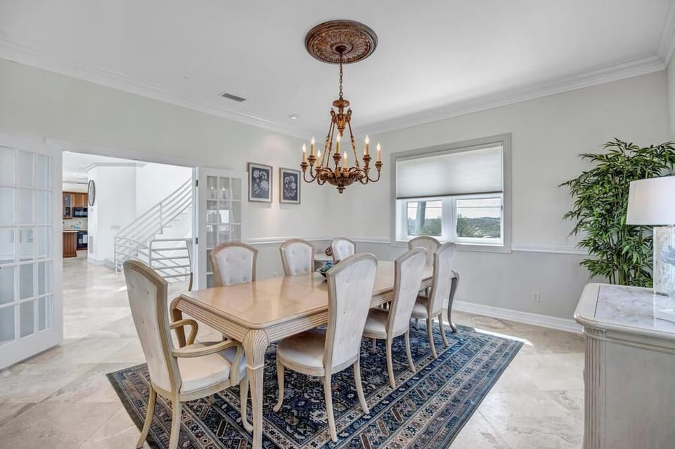 - French doors open to the dining room with ample natural light and graceful trim
- Warm chandelier hangs over a polished wood table perfect for group dinners
- Traditional style meets comfort in this bright, relaxing gathering space