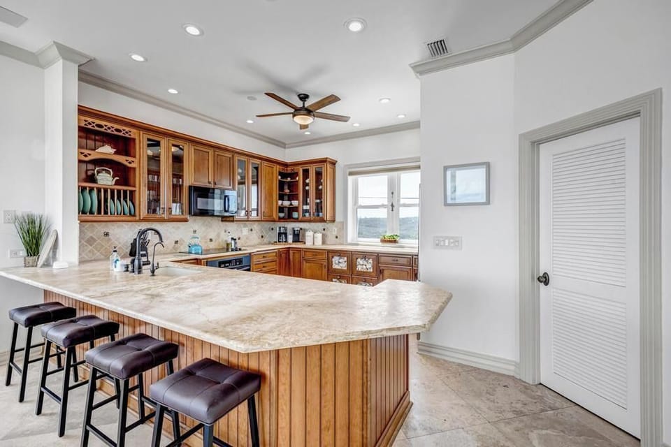 - Wraparound granite island with seating for four makes it great for gatherings
- Wood cabinetry, recessed lighting, and a ceiling fan offer comfort and charm
- Convenient layout for cooking, dining, and entertaining in one shared area