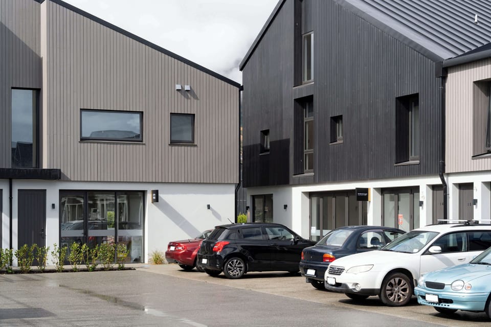 Modern townhouses with stylish vertical cladding in contrasting tones of grey and charcoal, offering secure and convenient off-street parking right at the doorstep