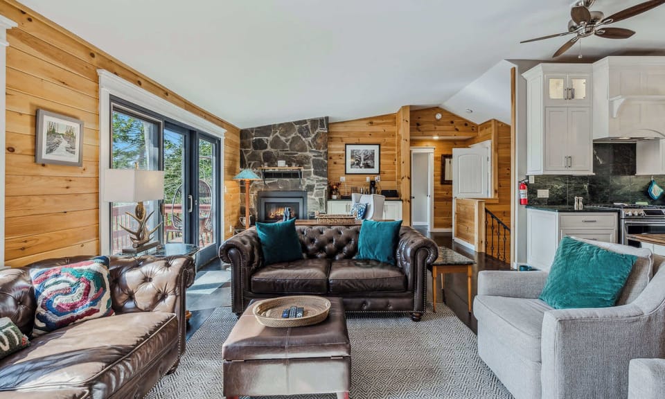 Open-concept living room with stone fireplace, leather sofas, and views into the fully equipped kitchen