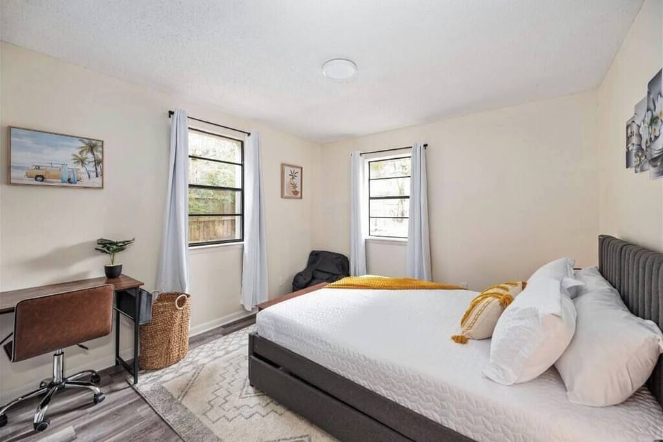 Serene bedroom w/ soft tones, cozy bed & natural light for a restful stay