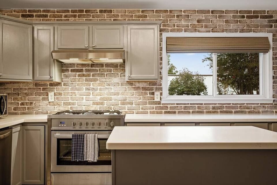 Stylish kitchen w/ warm tones, sleek counters & stainless appliances