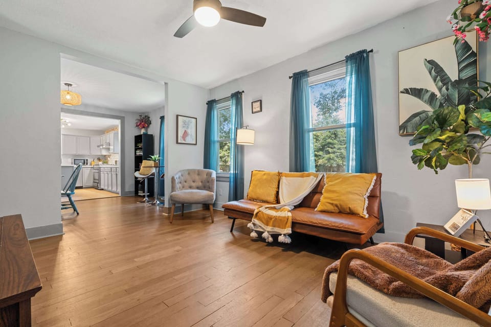 Bright living room w/ cozy seating, colorful accents & natural light pouring through windows