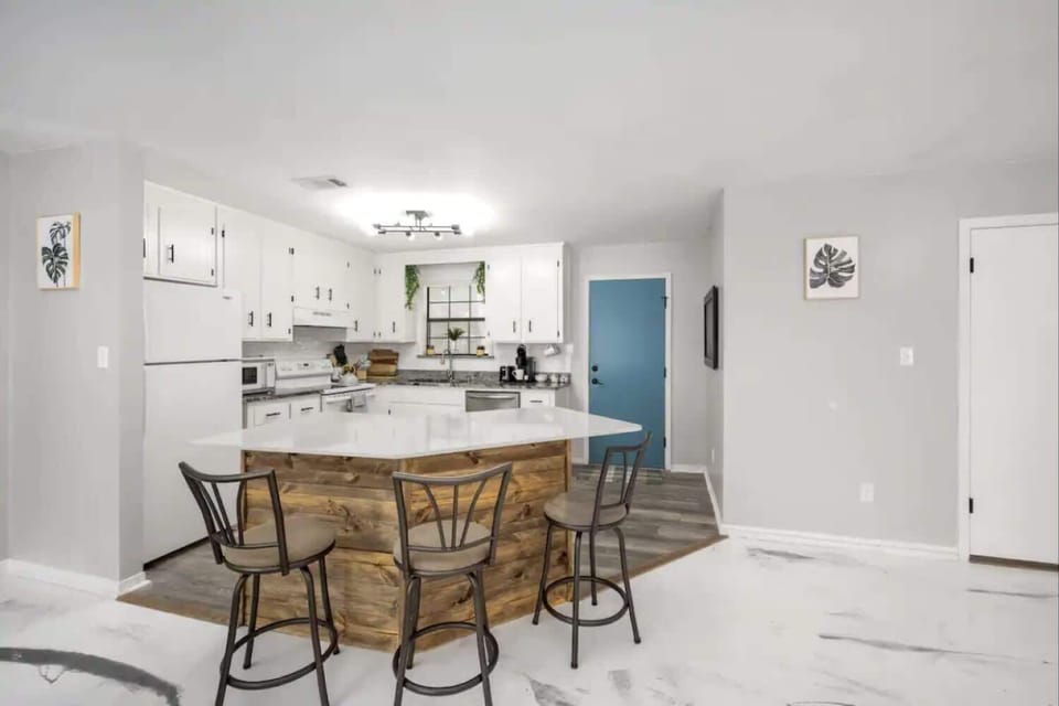 Dining area w/ wood table & bar seating, seamlessly connected to the bright kitchen