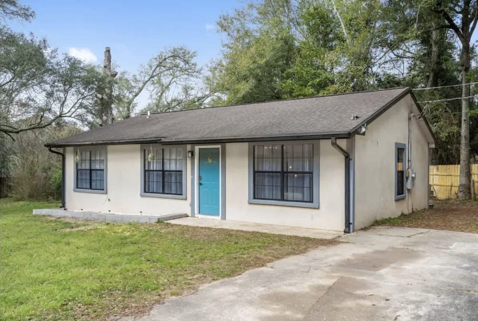 Welcoming single-story home exterior w/ driveway, lawn & mature trees