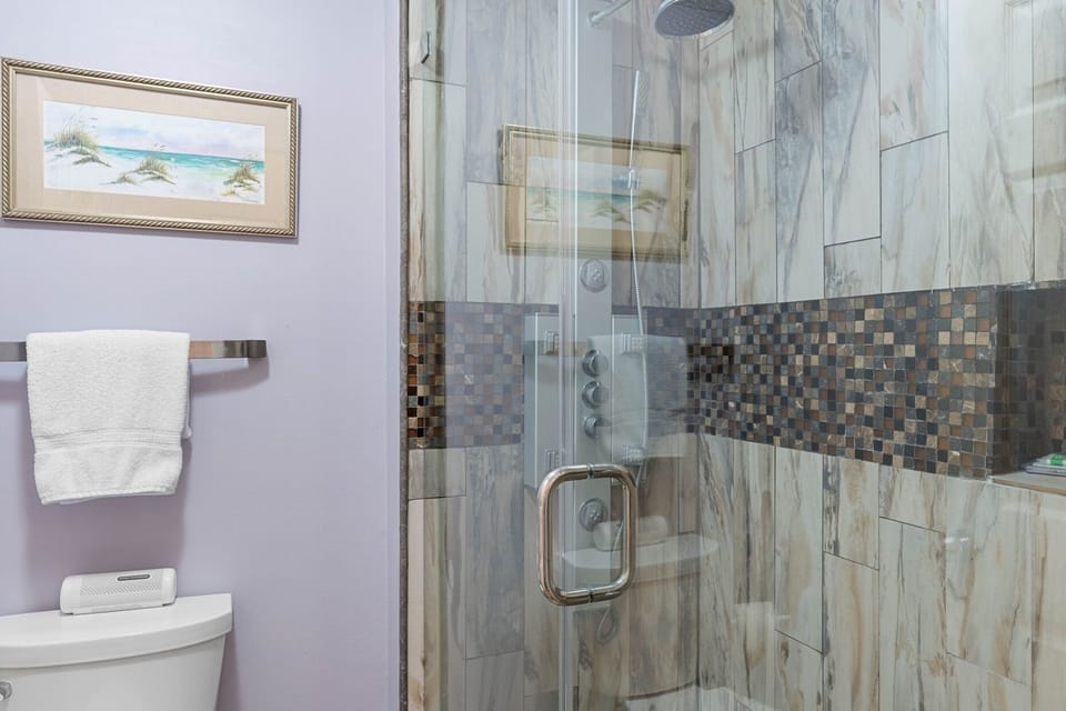 Clean bathroom setup w/ tub & shower combo, bright lighting & simple finishes.