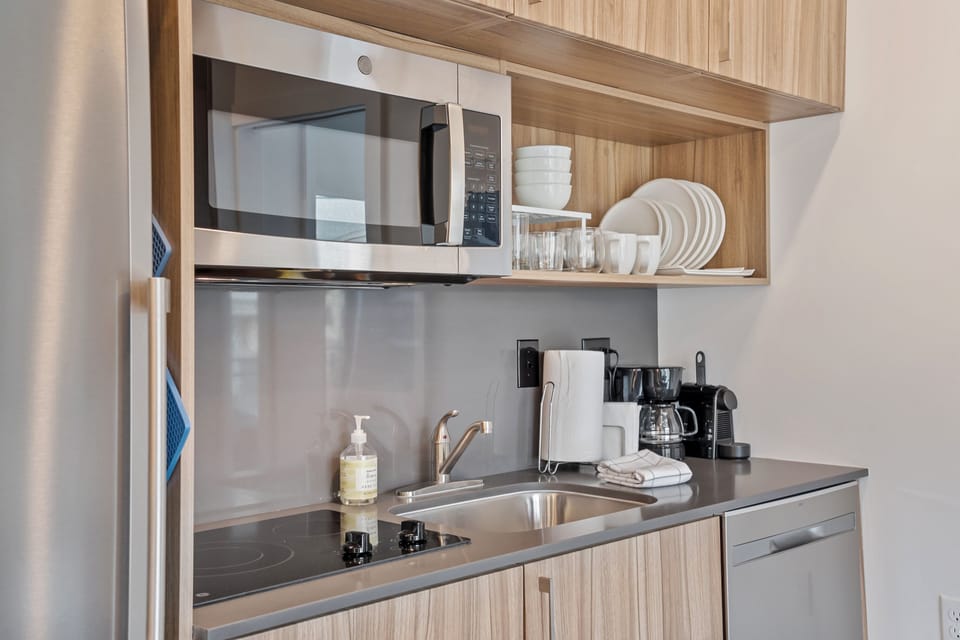 Microwave, garbage disposal, dishwasher, stove top, plates, silverware, drip coffee maker