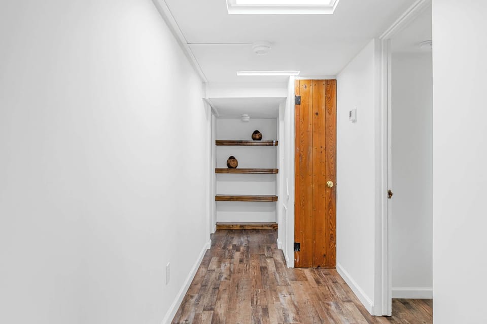 Hallway with wood flooring, built-in shelves, and a rustic wooden door