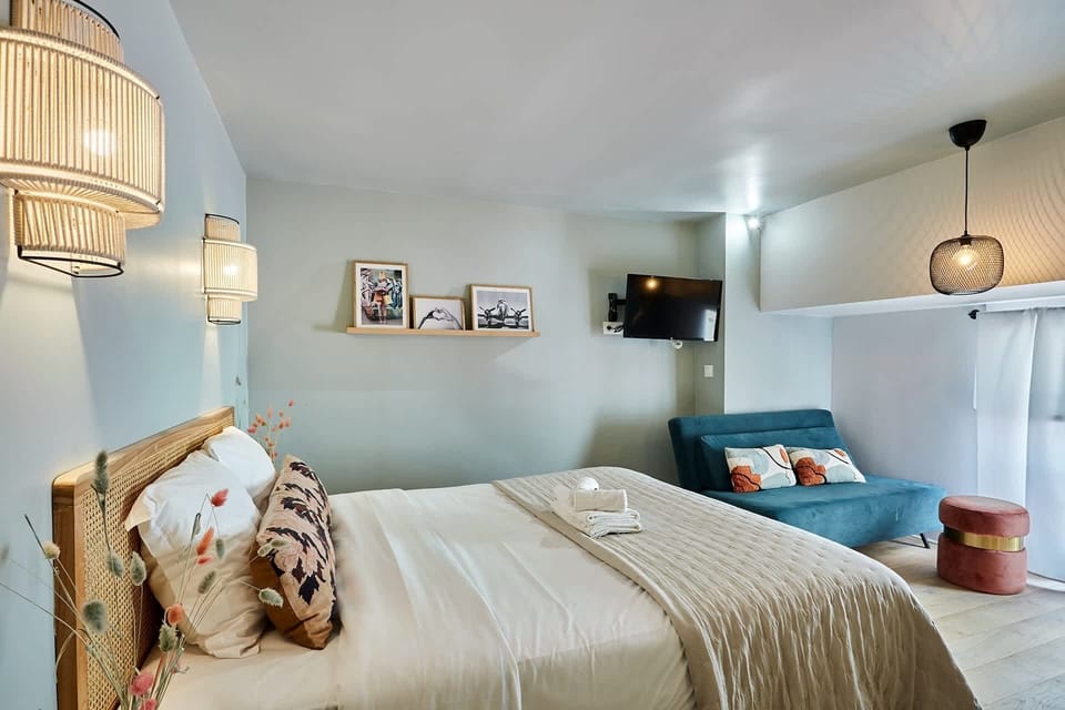 Grand studio avec lit double, un canapé lit simple, TV, coin repas et cuisine ouverte équipée.