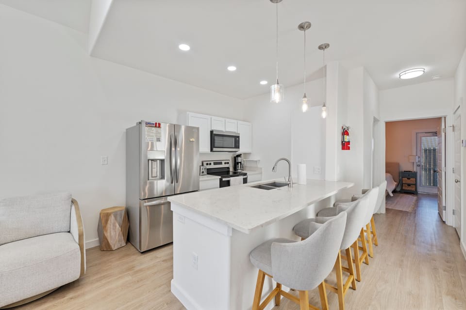 Your modern kitchen features sleek white countertops, stainless steel appliances, and stylish pendant lighting perfect for cooking memorable meals.