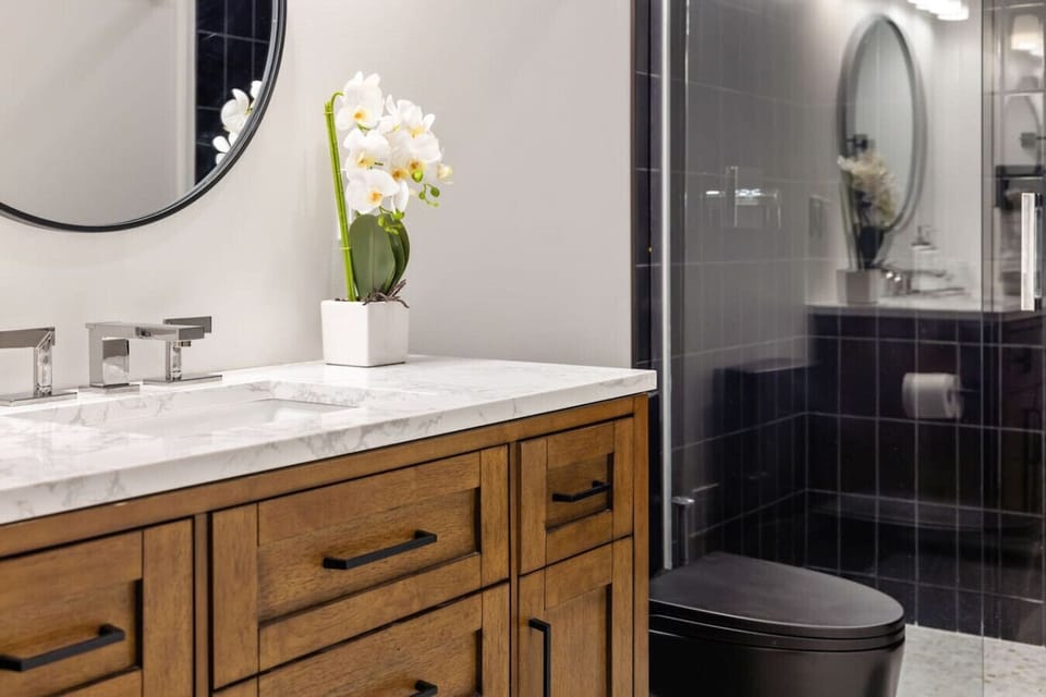 Moody & Modern – This rich-toned bathroom pairs dark tile with warm wood for both an extravagant and grounding feel.