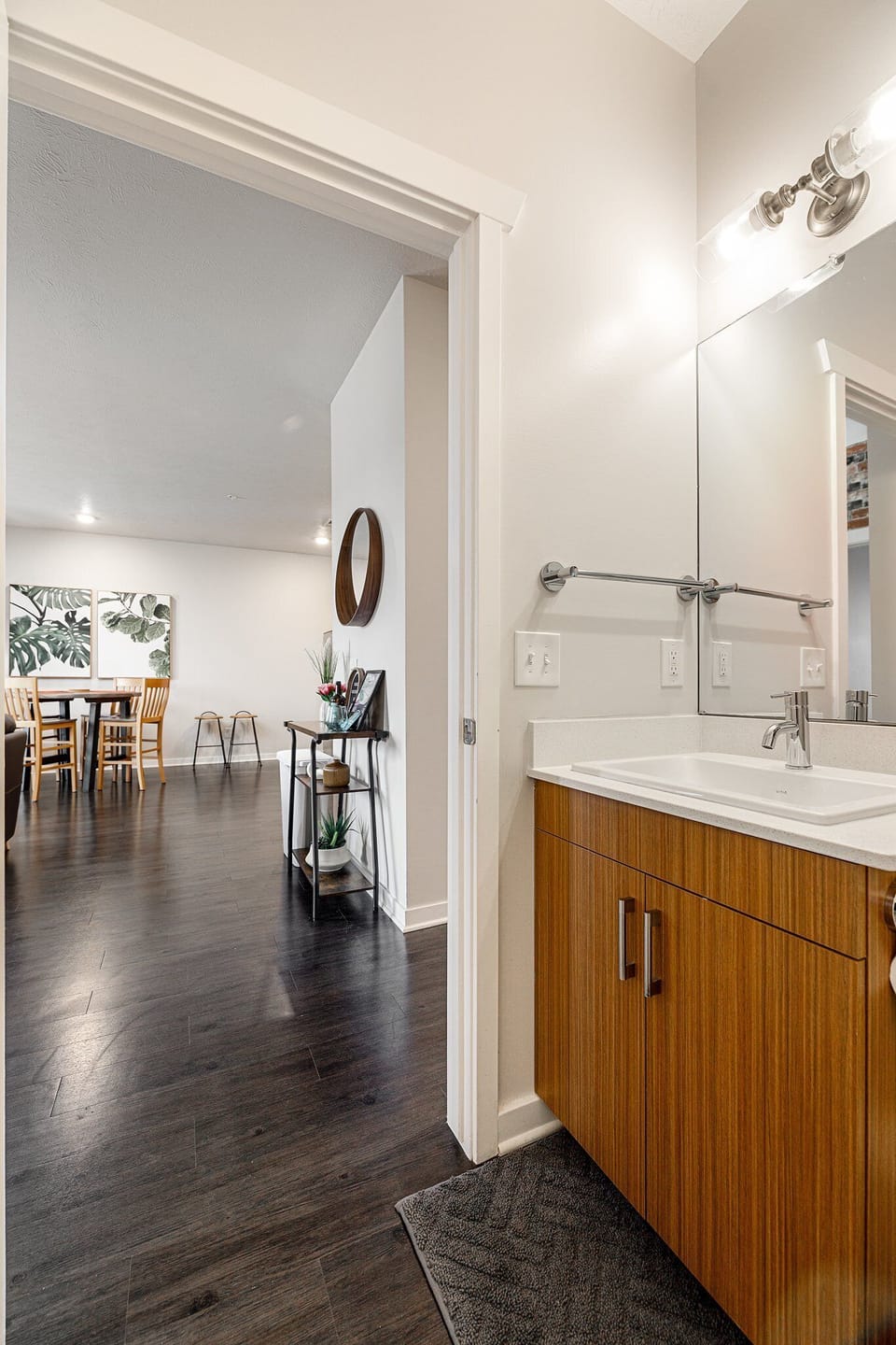 Entry view w/ sleek vanity & mirror leading into the bright open living space.