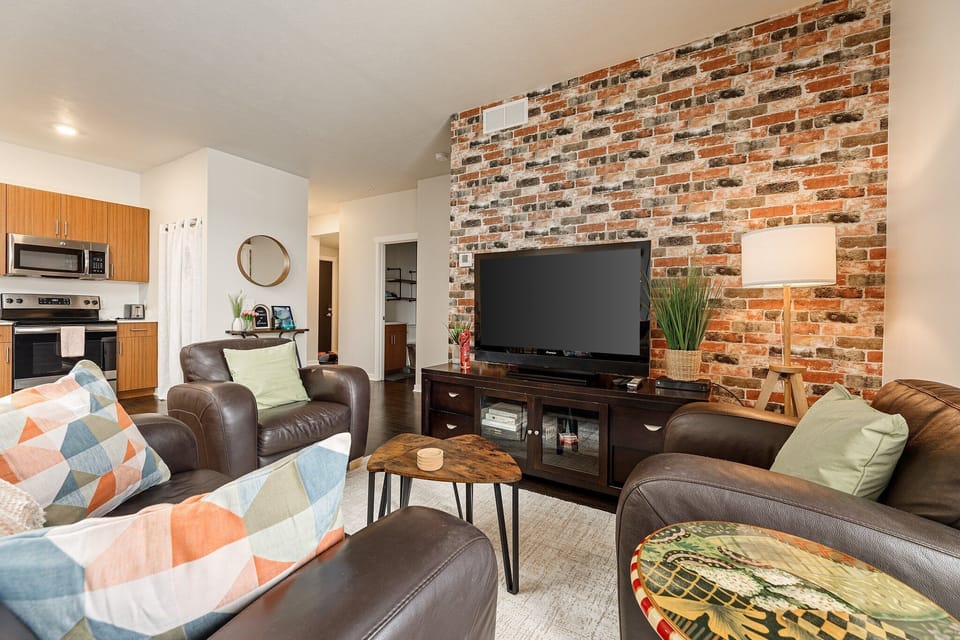 Stylish living area w/ exposed brick accent wall, comfy seating & a TV for cozy nights in.