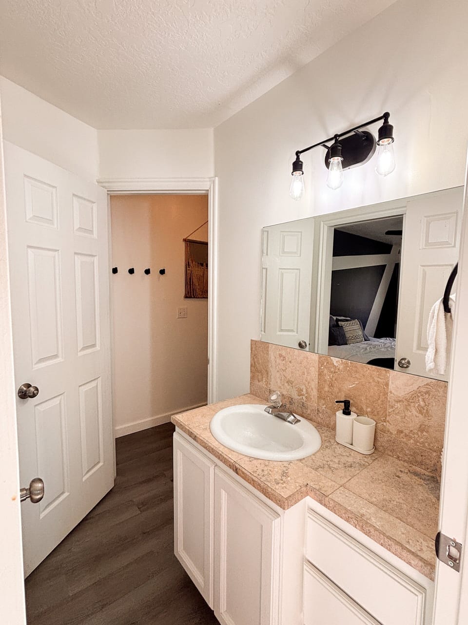 Vanity area - sink, mirror, tile counter, glimpse into bathroom.