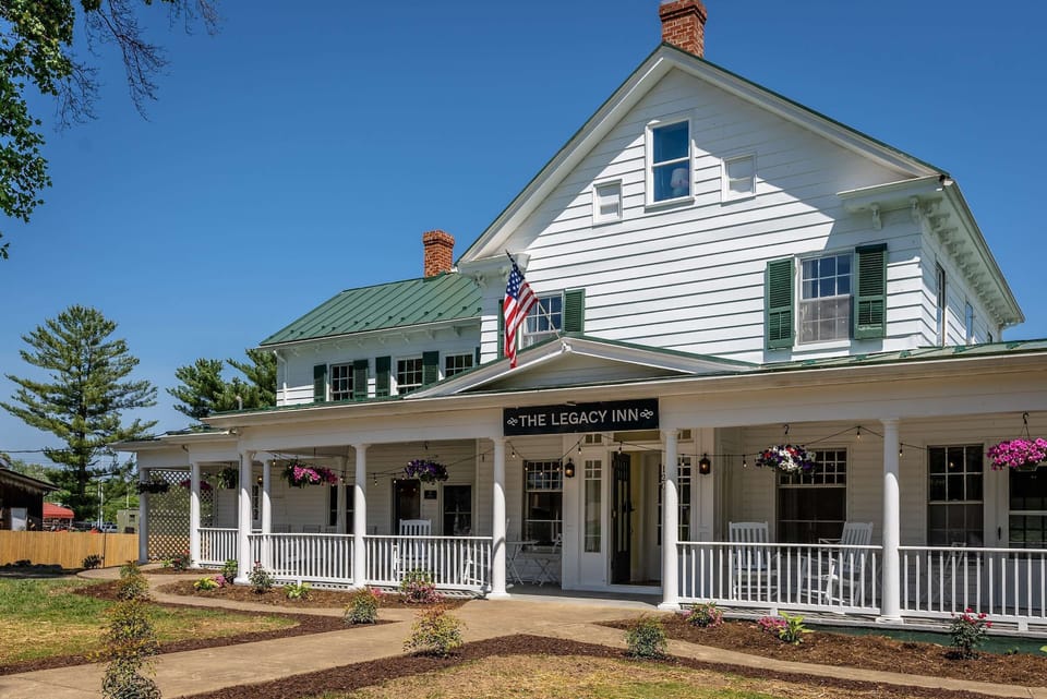 Historic inn with a spacious porch featuring rocking chairs and hanging flower baskets