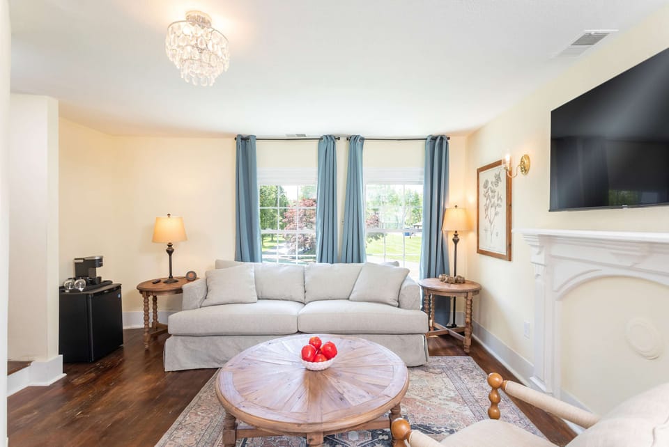 Relax in the bright living room featuring a comfortable sofa, wooden coffee table, and large windows with blue curtains.
