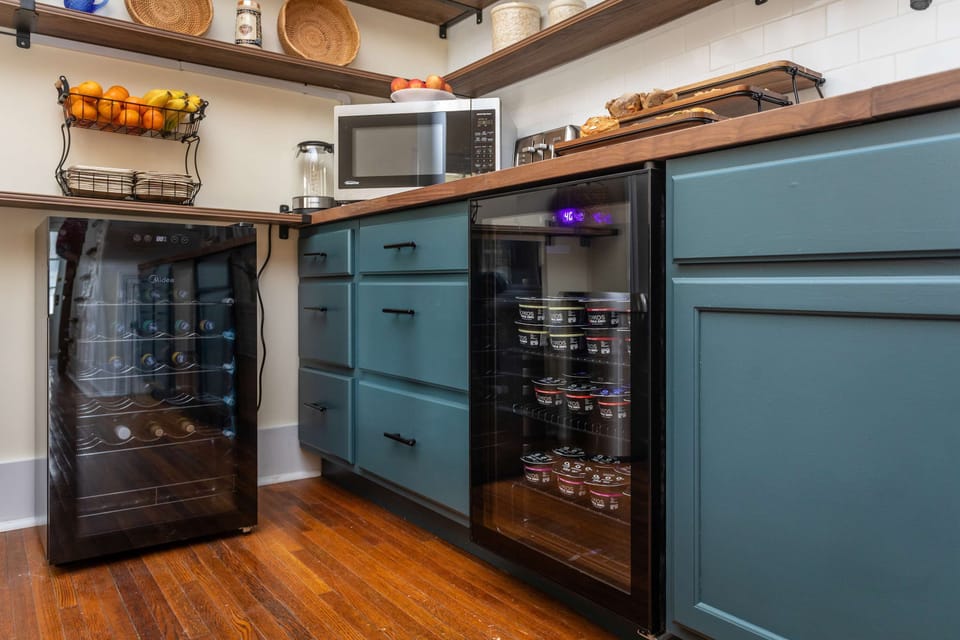 Modern kitchen corner with teal cabinetry and dual beverage coolers for convenience.