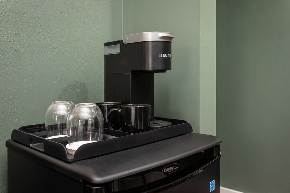 Compact coffee station with a Keurig machine and glassware for convenient brewing.