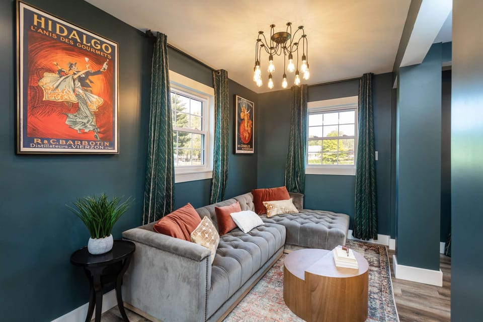Cozy living room with a tufted sectional sofa and vintage art on teal walls.