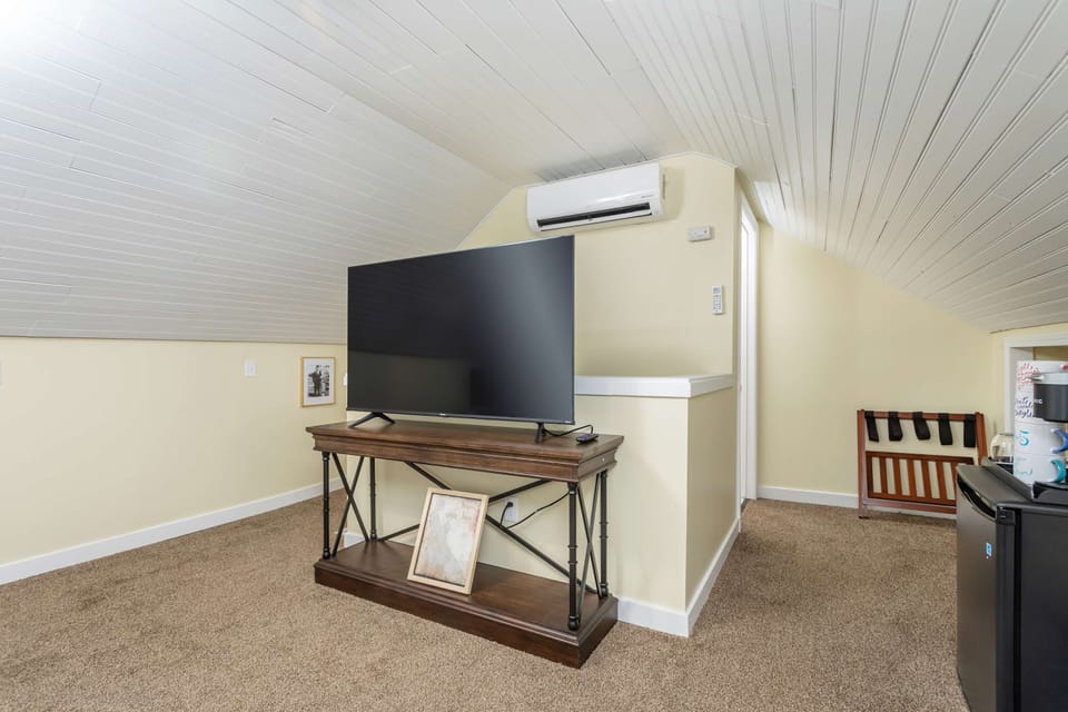 Cozy attic space with a large flat-screen TV and air conditioning for comfort.