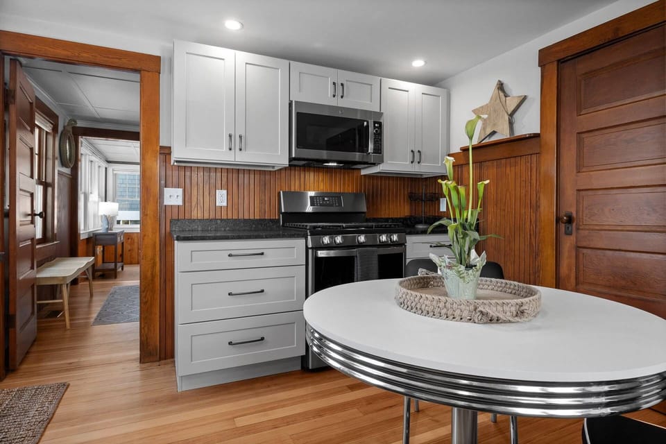 Another view of the kitchen with small dining table, stove, microwave, and view into the TV room and dining room