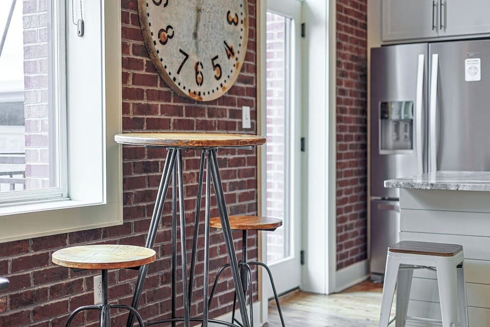Dining Nook: Rustic charm meets modern flair with a chic table and stunning brick backdrop!