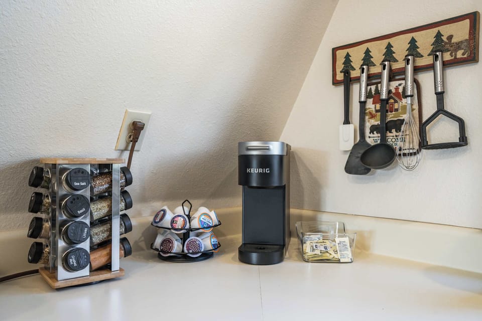 Enjoy your morning brew with a fully stocked coffee station, complete with a Keurig, a selection of pods, and essential cooking tools at your fingertips.








