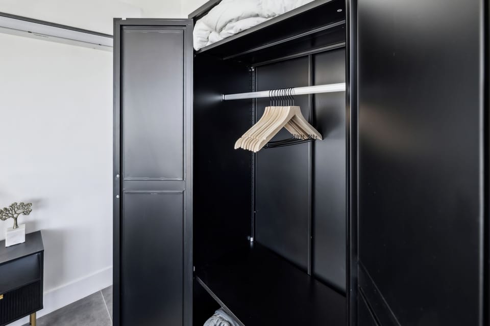 Hang clothes wrinkle-free & find extra bedding in our tall black wardrobe.