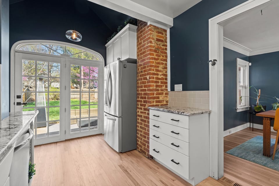 Charming kitchen entry to the backyard, featuring French doors, exposed brick, and bright natural light