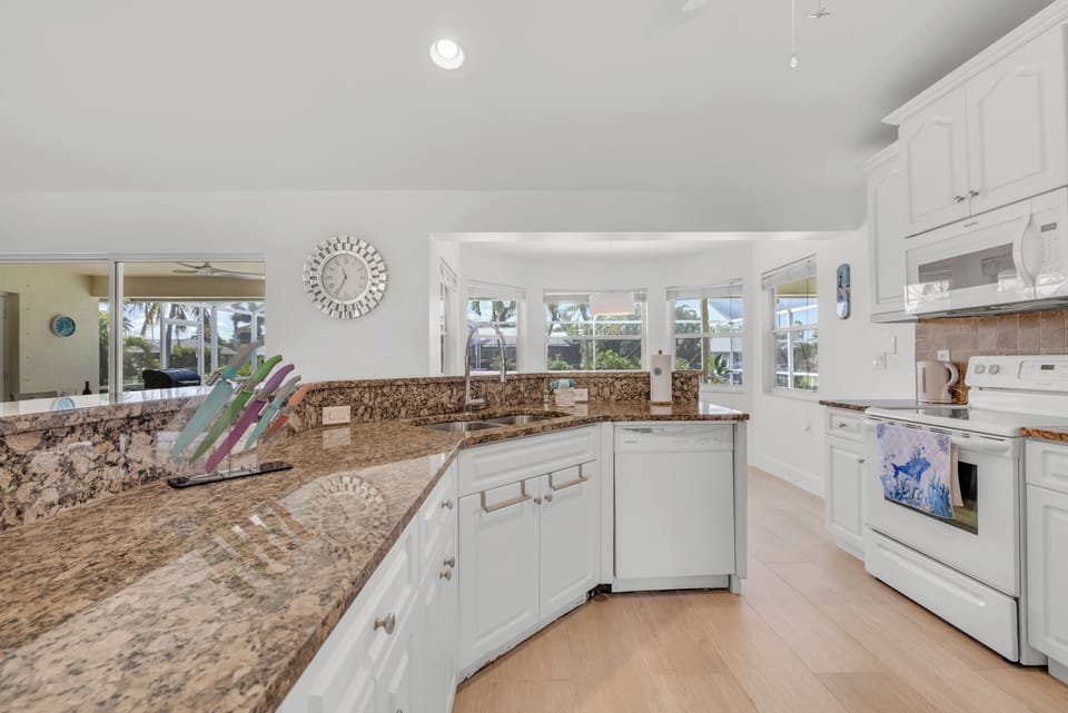 - Cook in style with wraparound granite counters, white cabinetry, and sunny window views
- Double sink, full appliances, and plenty of prep space make meal time a breeze
- Inviting kitchen that blends warmth with functionality