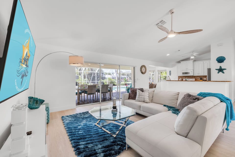 - Open concept layout keeps the kitchen, living, and dining areas bright and unified
- Comfortable sectional, modern fan, and beachy details create a relaxed vibe
- Easily transition from TV time to poolside fun with slider access