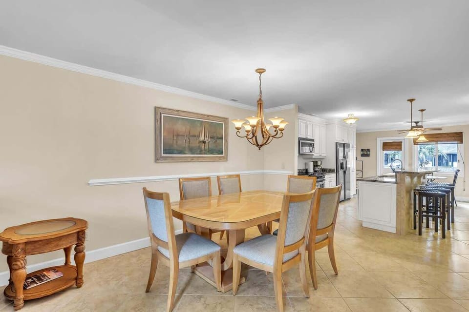 Open dining area with seating for six adjacent to a modern kitchen with breakfast bar.