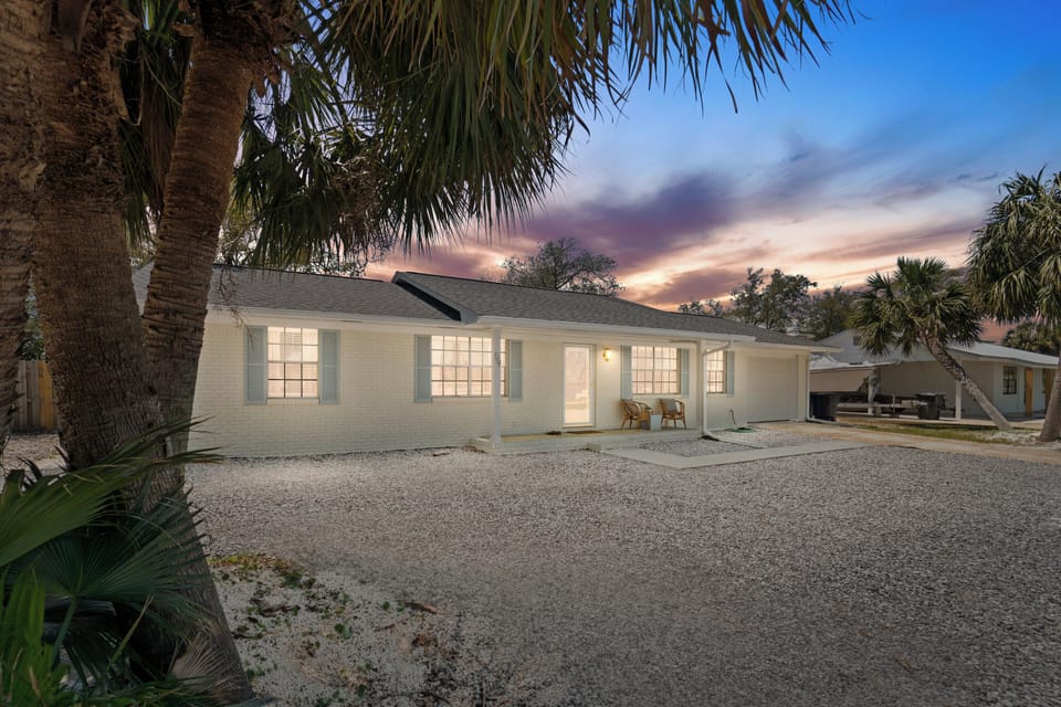 A charming beachside cottage surrounded by tropical palms offers a peaceful retreat with spectacular sunset views and convenient gravel parking.