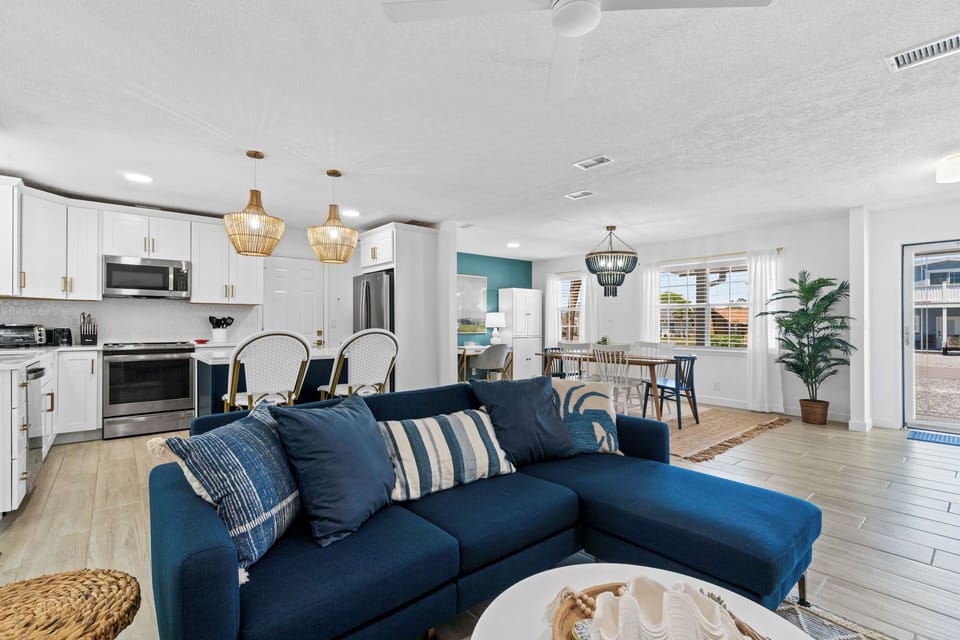 Unwind in your stylish open-concept space where coastal charm meets modern comfort, complete with a plush navy sofa and fully equipped kitchen.
