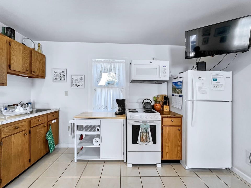 Fully stocked kitchen with essentials including a stove, fridge, microwave, and even a coffee maker.