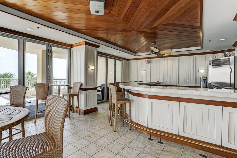 Spacious lanai with bar seating, ceiling fan, and coastal views — perfect for relaxing, entertaining, or enjoying drinks. Stylish indoor-outdoor space with island-inspired charm.
