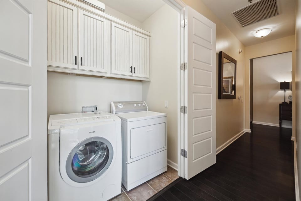 Laundry area includes a front-load Bosch washer and a top-load dryer, with built-in overhead cabinets for convenient storage.