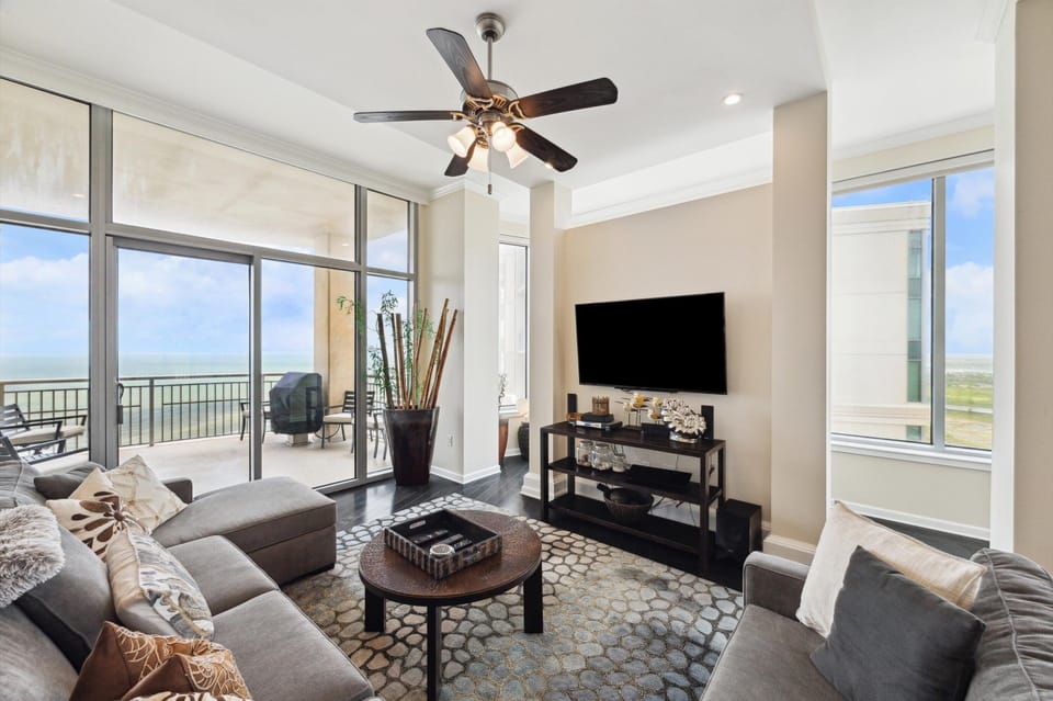 Bright and modern living room with expansive Gulf views, floor-to-ceiling windows, and direct balcony access.